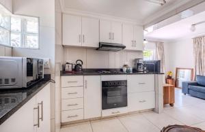 a kitchen with white cabinets and a microwave at La Lucia Sleepover in Durban