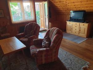 a living room with two chairs and a television at Chalupa 58 in Štiavnické Bane