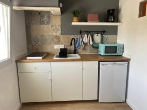 a kitchen with white cabinets and a blue microwave at Casa Alto da Vela in Peniche