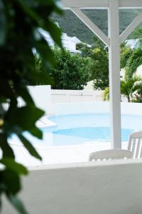 a swimming pool with two white chairs next to it at Quiet loft studio - Pinel side in Cul de Sac