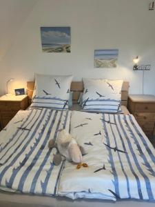 a teddy bear sitting on a bed with birds on it at Gemütliches Inselnest mit großer Terrasse nahe Nordsee& Hafen in Tönning