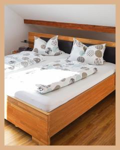 a bedroom with a wooden bed with white sheets and pillows at Schwarzwaldpension Tuttlingen in Tuttlingen