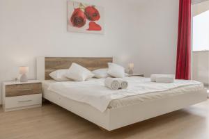 a white bedroom with a bed with two towels on it at Peacefull Apartment with Garden and Barbeque in Biograd na Moru