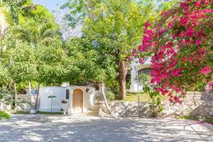 a white house with a tree with pink flowers at Villa Bruga en Samara Rocks in Sámara