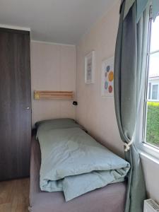 a small bedroom with a bed and a window at ZEEMEEUW - Platz 31, Olmenduin in Serooskerke