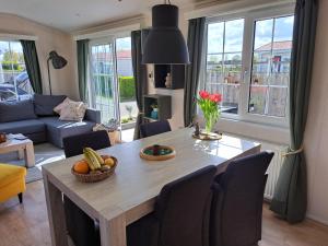 a living room with a dining room table and a living room with a couch at ZEEMEEUW - Platz 31, Olmenduin in Serooskerke