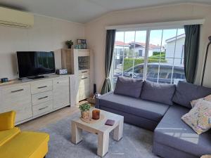 a living room with a blue couch and a tv at ZEEMEEUW - Platz 31, Olmenduin in Serooskerke