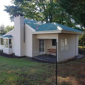 een klein wit huis met een hek ervoor bij 37 Valley View Cottage in Underberg