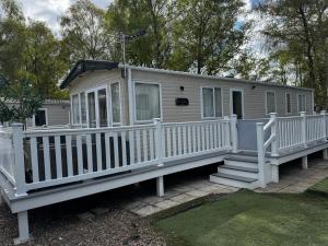 a mobile home with a porch and a white railing at Tattershall Lakes 49 Larch View in Tattershall