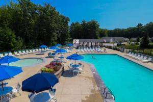 a large pool with blue umbrellas and chairs and tables at Selkie Village in Wells