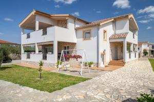 a white house with a playground in front of it at Peacefull Apartment with Garden and Barbeque in Biograd na Moru
