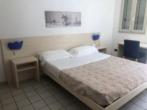 a bedroom with a bed and two tables and a window at Hotel Sirenetta in Isola delle Femmine
