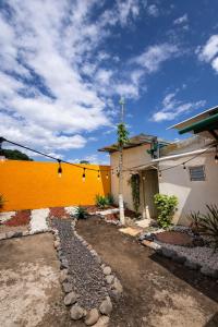 a house with a yellow wall next to a driveway at Tico-living in Alajuela