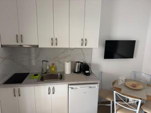 a kitchen with white cabinets and a sink and a table at Alexander in Ierissos