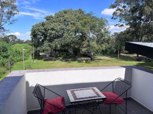 a balcony with two chairs and a table with red pillows at Loto San Lorenzo Studio I balcón, vista cerros y piscina in San Lorenzo
