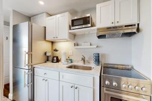 a kitchen with white cabinets and a stainless steel refrigerator at Splash & Relax Unit 203 in Wells