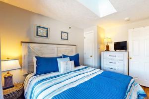 a bedroom with a bed with blue sheets and a television at Splash & Relax Unit 203 in Wells +29 photos