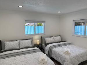 a bedroom with two beds and two windows at Ebenezer Home in Hallandale Beach +26 photos