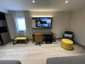 a living room with a tv and a desk with a chair at Le Grand Hotel St-Georges in Saint-Georges
