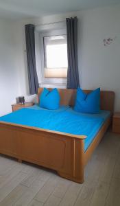 a bed with blue pillows in a room with a window at Franzenhof Beldorf in Beldorf