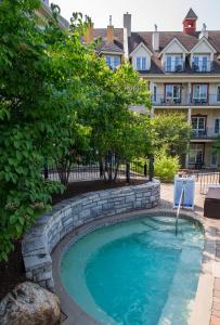 a swimming pool in a yard with a stone retaining wall at Tour des Voyageurs in Mont-Tremblant