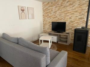a living room with a couch and a tv at Maison Basse in Malestroit