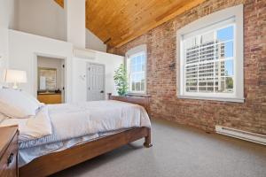 a bedroom with a brick wall and a bed and windows at Gorgeous downtown apartment with loft in Hartford