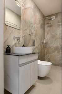a bathroom with a white sink and a toilet at Antimo Villas - Gallini Beach House in Zakynthos