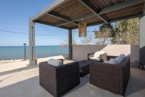 a patio with a table and chairs and the ocean at Antimo Villas - Gallini Beach House in Zakynthos