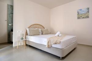 a white bedroom with a bed with white sheets and pillows at Antimo Villas - Gallini Beach House in Zakynthos