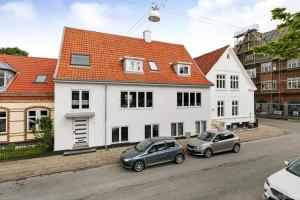 two cars parked in front of a white house at Penthouse - 3BR - Esbjerg Island in Esbjerg