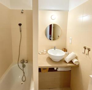 a bathroom with a sink and a tub and a mirror at Hôtel Bellevue Cap d'Agde in Cap d'Agde