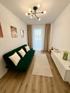 a living room with a green couch and a table at Emerald Stay in Şelimbăr