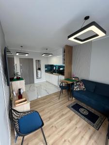 a living room with a blue couch and a kitchen at Apartament Calisia II in Kalisz