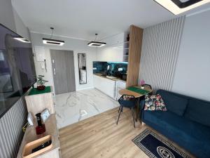 a living room with a blue couch and a kitchen at Apartament Calisia II in Kalisz