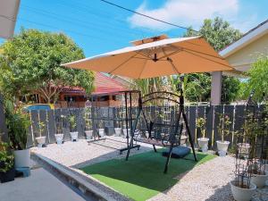 an umbrella and a swing with a green lawn at Homestay DAR AL - JUFRY fully aircond in Kuantan