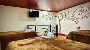 a room with two beds and a tree painted on the wall at MONTESANO Finca HOTEL in Jenesano