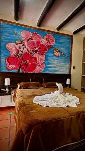 a bed with a painting of flowers on the wall at MONTESANO Finca HOTEL in Jenesano +15 photos
