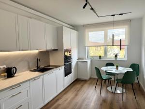 a kitchen with white cabinets and a table with chairs at Emerald Stay in Şelimbăr