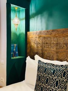a bedroom with a bed with a wooden headboard and a chandelier at Riad Mazal Mogador in Essaouira