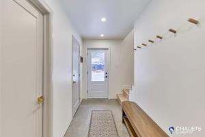 a hallway with a bench and a white wall at Chalet Altitude Riverfront Pet-Friendly in Saint-Raymond