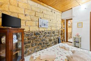 a bedroom with a stone wall with a bed and a tv at Bed and Breakfast Cala Luna in Castelsardo