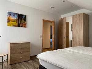 a bedroom with a white bed and a wooden dresser at Am Irrenbächle in Albstadt