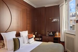 a bedroom with a bed and a desk and a window at Hôtel d'Argenson in Paris