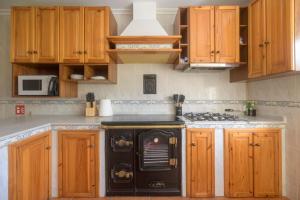 a kitchen with a black stove and wooden cabinets at Casa Salamó in Ampuero