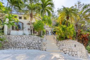 a stone staircase leading to a white house with palm trees at Villa Sandy en Samara Rocks in Sámara