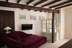a living room with a red couch and a tv at Chic et Charme Cottage in Suzay