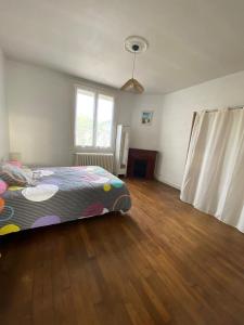 a bedroom with a bed and a wooden floor at Logement proche centre-ville in Bourges