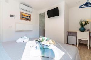 a white bedroom with a bed with a tv on the wall at B&B Morrocoy Beach in Marina di Camerota
