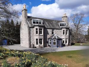 a large stone house with yellow flowers in front of it at Achnagonlin House in Grantown on Spey